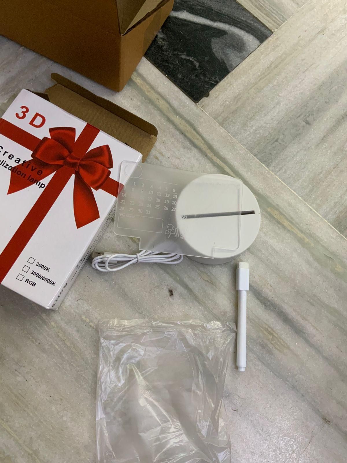 White electronic device with cable, packaging, and pen on a marble surface