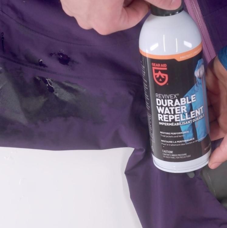 Revivex Durable Water Repellent spray bottle held over a purple jacket.