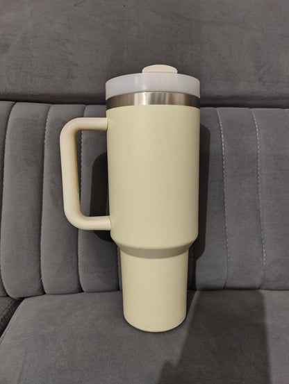 Beige travel mug with a silver lid on a gray couch