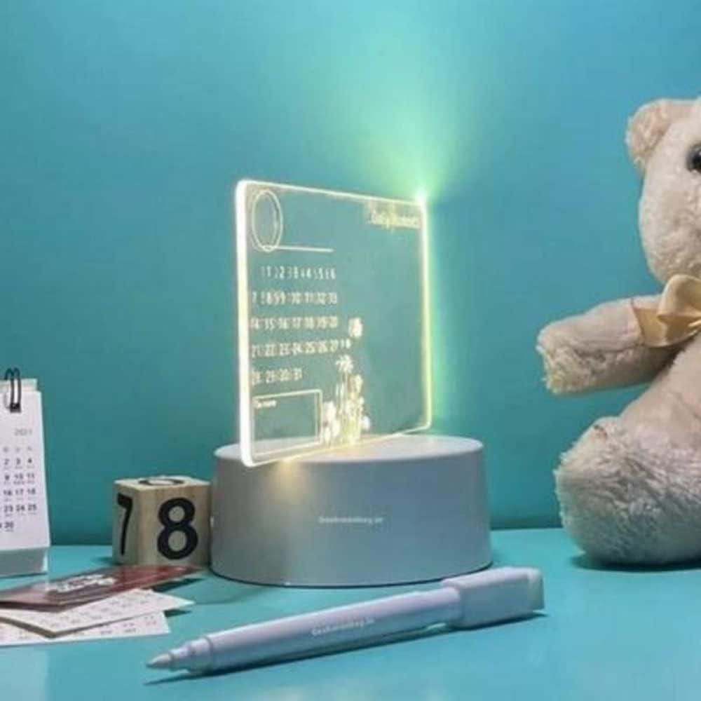 Decorative LED sign on a stand with a teddy bear and calendar in the background.